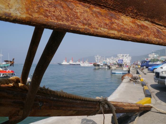 육중한 철제 닻 사이로 보는 항구의 모습