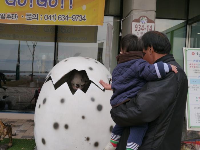 거대한 알까기 모형 앞의 자상한 아빠와 아기
