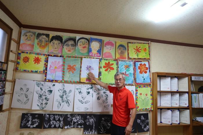 반교마을 조권영 이장님께서 할머니 화가들이 그린 그림을 가리키며 설명을 해 주고 계시다.