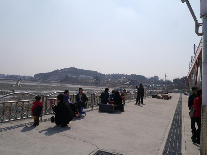 수산물센터 바로 뒤에서 햇빛을 받으며 겨울 항포구를 즐기는 관광객들