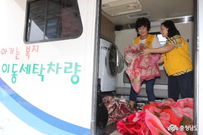 이동빨래방차량에서 봉사자들이 주민들이 맡긴 빨랫감을 세탁기에 넣고 있다. 