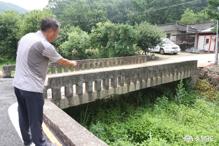 한 주민이 오래된 마을다리를 가리키며 안전을 위해 새로운 다리가 세워지길 바라고 있다.