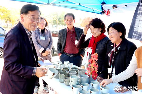 ㄱ오주시의회 박병수 시의장이 분청사기 찻잔을 고르며 회원들과 담소를 나누는 장면
