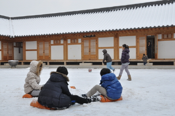눈이 온 공주한옥마을 마당에서 아이들이 뛰어놀고 있다.