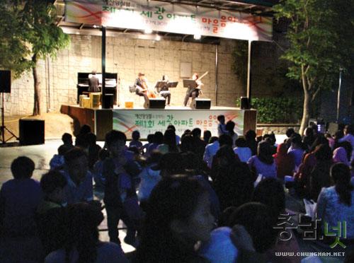 21일 저녁, 세광아파트 문화체육광장에 마련된 무대에서 펼쳐지고 있는 예산앙상블의 연주를 주민들이 편안한 자세로 앉아 감상하고 있다.
