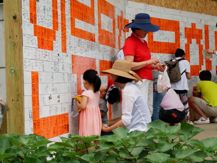 타일벽화꾸미기에 참여해 타일에 글을 쓰고 있는 관광객들.
