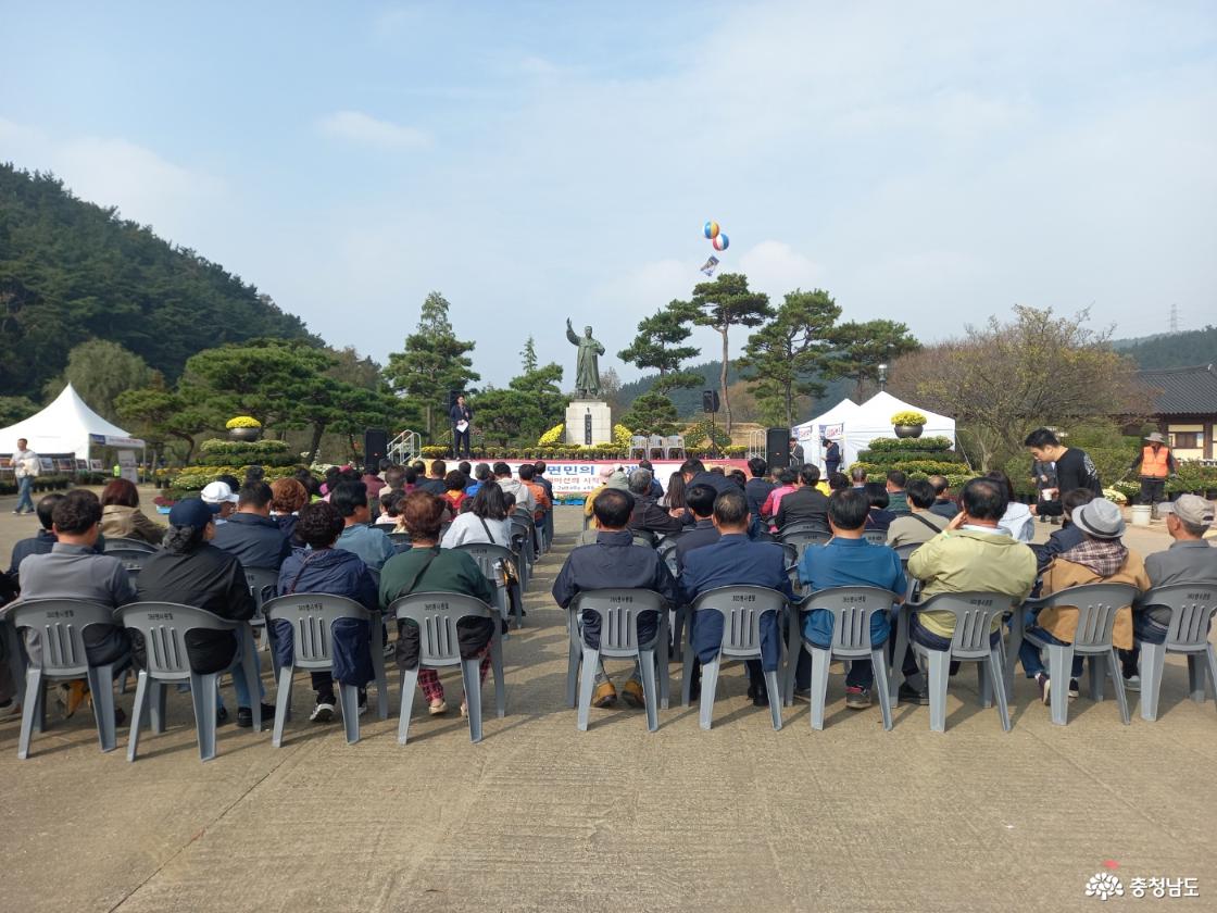 무대 앞에서 사회자가 사회를 보고 그 앞에 마련된 간의 의자 객석에 100여명이 넘는 관람객이 앉아서 공연을 관람하고 있다..