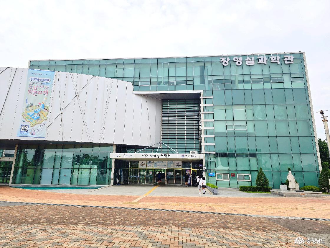 아산환경과학공원 안에 위치한 장영실과학관 외관 모습으로, 유리 건물 전면과 입구, 장영실 동상이 함께 보이는 과학 체험 시설 전경입니다.