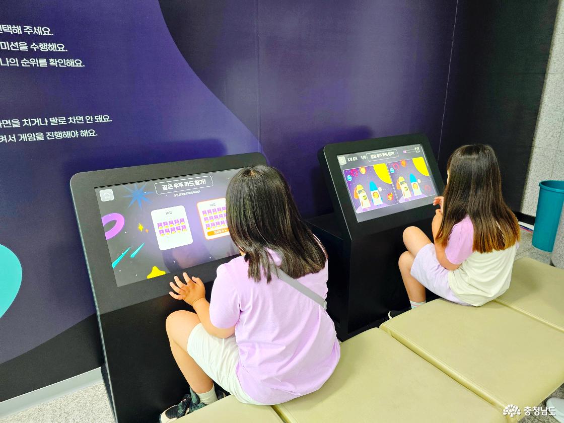 아이들이 장영실과학관 우주 과학 전시존에서 터치스크린을 이용해 같은 우주 카드 찾기와 미션 게임을 체험하고 있는 모습입니다.