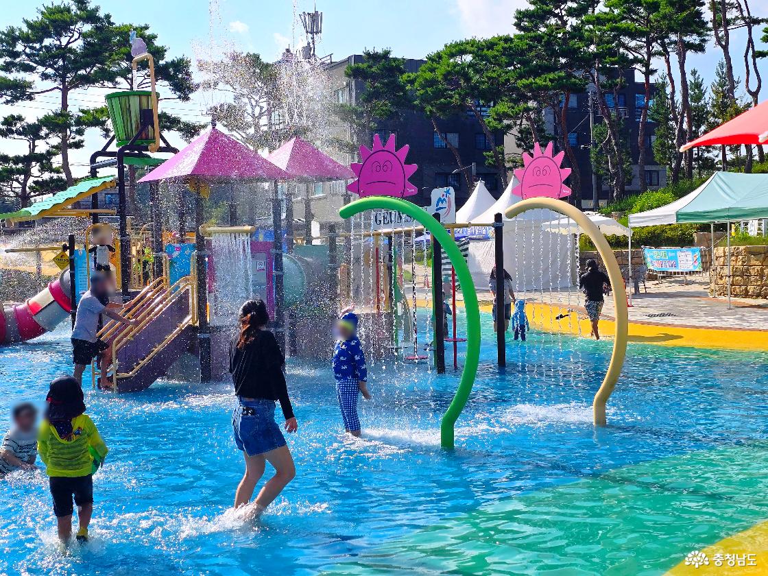 대형 물바구니와 미끄럼틀, 그늘막을 한눈에 볼 수 있는 금산 아인수림공원 물놀이장 전체 모습