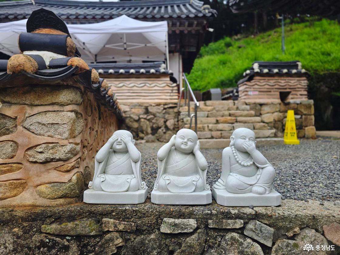 동학사 돌담 앞에 놓인 보지 말고 듣지 말고 말하지 말라는 의미의 동자승 조형물