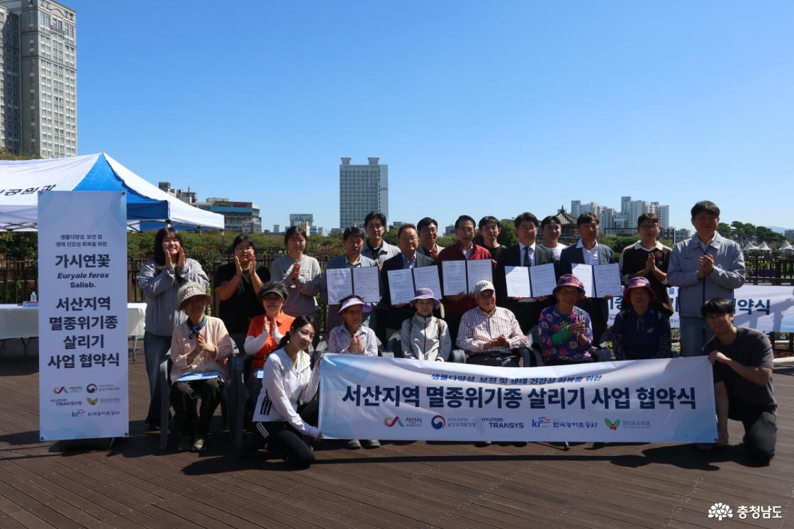 &lsquo;서산지역 멸종위기종 살리기 사업 협약식&rsquo; 참석자들이 중앙호수공원 희귀식물 특화정원 앞에서 기념촬영을 하고 있다.