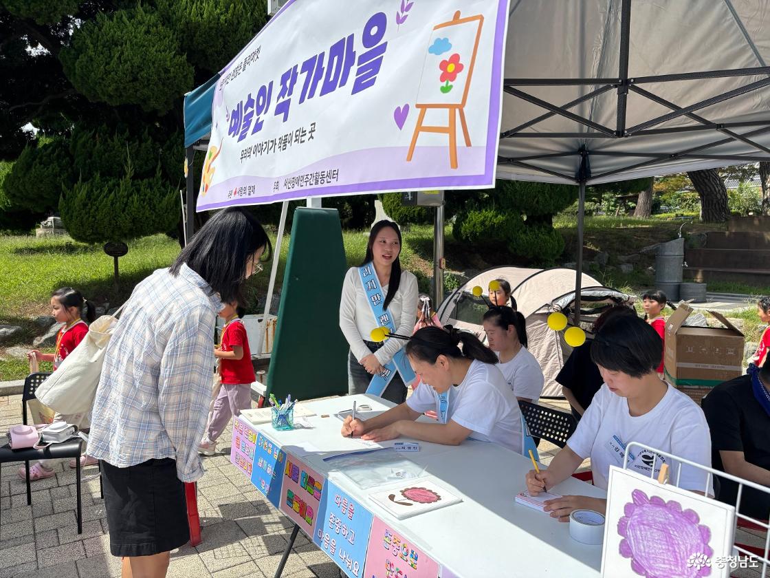 &lsquo;예술인 작가마을&rsquo; 부스에서 센터 이용인이 방문객에게 자신의 작품을 소개하고 사인을 하고 있다. 센터는 시&middot;수필과 그림에 재능을 가진 이용인들이 직접 작가로 시민들을 만날 수 있도록 부스를 마련했다.